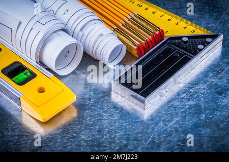 Metro di legno prova livello di costruzione quadrato e Blueprints su metallico graffiato superficie costruzione e concetto di architettura. Foto Stock