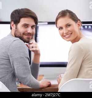 Che duo dinamico. Ritratto di due giovani professionisti sorridenti alla loro scrivania. Foto Stock