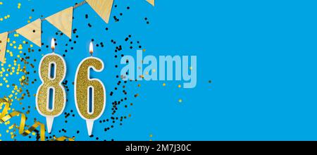 Candela d'oro numero ottantasei. Cartellino di compleanno o anniversario con l'iscrizione 86 su sfondo blu. Celebrazione dell'anniversario. Banner. Foto Stock