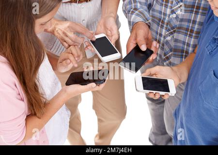 La nostra famiglia ama condividere le cose... tramite i nostri smartphone. Foto ritagliata di una famiglia in piedi con i loro smartphone isolati sul bianco. Foto Stock