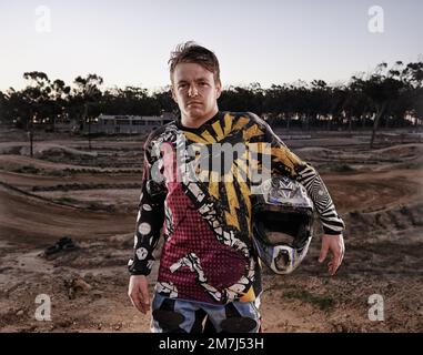 La passione viene con un po' di sporcizia. Ritratto di una corsa dirtbike in piedi nel suo ingranaggio da corsa. Foto Stock