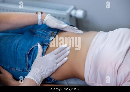 Medico che esamina il ventre delle femmine e palpandolo delicatamente Foto Stock