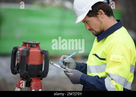 topografo sul terreno al lavoro in cantiere Foto Stock