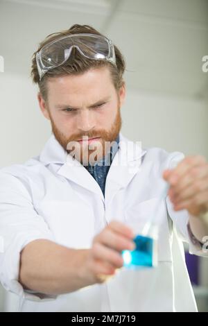 un lavoratore di sesso maschile che tiene liquidi in laboratorio Foto Stock
