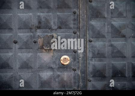 Vista frontale della porta in ferro nero intemperiato con serratura e serratura Foto Stock