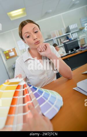 Signora con cliente, tenendo grafici a colori Foto Stock