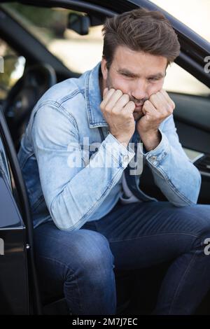 un uomo preoccupato sedette nella sua auto parcheggiata Foto Stock