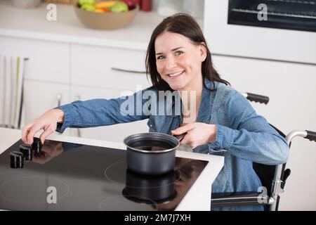 giovane donna in sedia a rotelle cucina Foto Stock