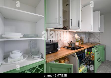 Le porte si aprono e i cassetti si aprono su nuovi mobili da cucina verdi e bianchi Foto Stock