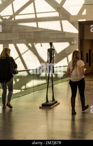 Due donne che camminano davanti alla scultura di Alberto Giacometti: Walking Man II, 1960, piano superiore - Ponte, Galleria Nazionale d'Arte - edificio Est, Washingto Foto Stock