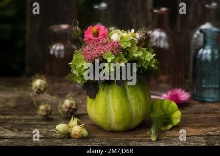 Zucca cava con decorazione floreale su una panca da giardino Foto Stock