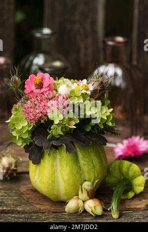 Zucca cava con decorazione floreale su una panca da giardino Foto Stock