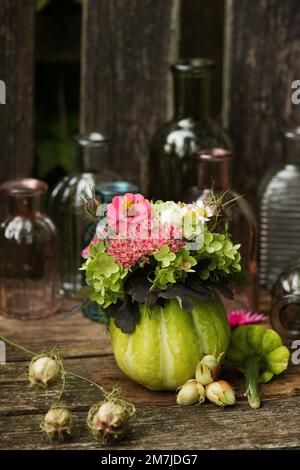 Zucca cava con decorazione floreale su una panca da giardino Foto Stock