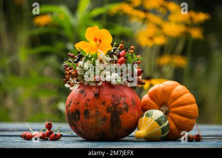 Zucca cava con decorazione floreale su un tavolo da giardino Foto Stock