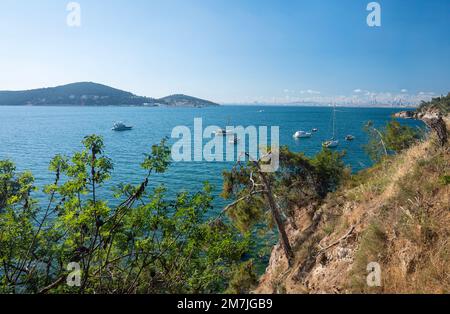 Splendida vista panoramica sul Mar Nero con gli yacht e la città sullo sfondo. Costa rocciosa con alberi e pini in una soleggiata giornata estiva. Turchia, Foto Stock