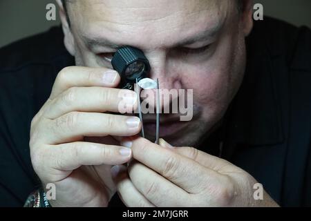 Kapstadt, Sudafrica. 26th Ott 2022. Yair Shimansky, fondatore dell'omonimo marchio sudafricano di gioielli, analizza un diamante con una lente d'ingrandimento nel suo negozio di gioielli a Città del Capo. La guerra di aggressione russa contro l'Ucraina sta attualmente rafforzando la tendenza contro i diamanti da conflitto. Credit: Kristin Palitza/dpa/Alamy Live News Foto Stock