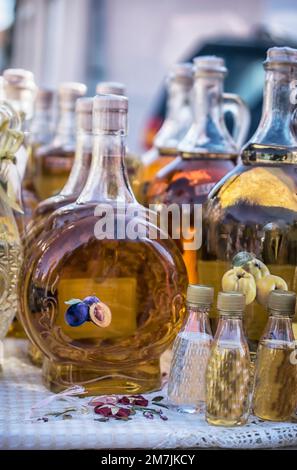 Distillati tradizionali balcanici in bottiglia presso la bancarella del mercato Foto Stock