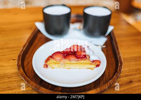 Crostata di fragole e due tazze Starbuck con caffè cappuccino serviti su un vassoio presso lo Starbucks Reserve Roastery Shop, Milano, Italia Foto Stock