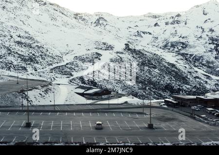 Una ripresa aerea di veicoli parcheggiati vicino ad edifici industriali e una montagna coperta di neve Foto Stock