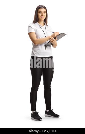 Ritratto completo di una allenatrice sportiva femminile che tiene un clipboard e sorride alla fotocamera isolata su sfondo bianco Foto Stock