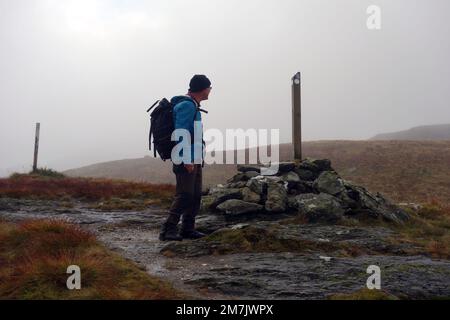 Uomo che guarda il cartello di legno 'Signpost' per il Loch Lomond & Cowel Way tra Lochgoilhead & Arrochar vicino a Coilessan Glen, Highlands scozzesi. Foto Stock