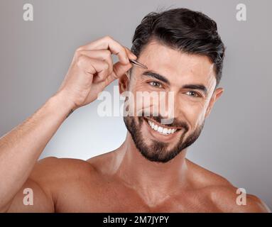 Uomo, pinzette per sopracciglia e rimozione dei peli del viso per la cura della pelle bellezza, il benessere e l'igiene sul fondo grigio dello studio. Modello sorriso Foto Stock