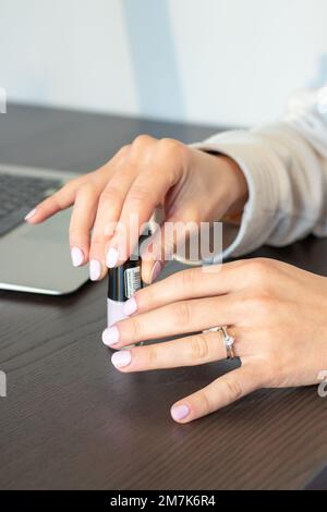 Un colpo verticale delle mani di una donna con uno smalto per unghie rosa pastello Foto Stock
