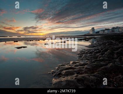 Tramonto a St Leonards sulla spiaggia di mare con la bassa marea. Marine Court in lontananza. Foto Stock