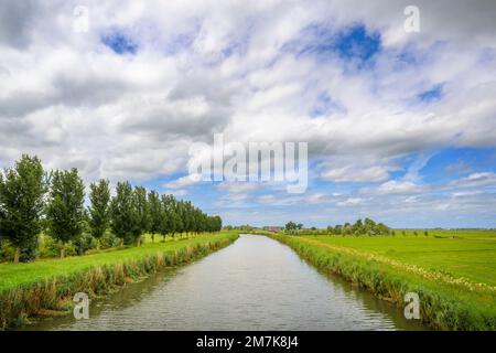 Tipico paesaggio fluviale olandese con prati verdi, canale e cielo blu e nuvole, Paesi Bassi. Foto Stock