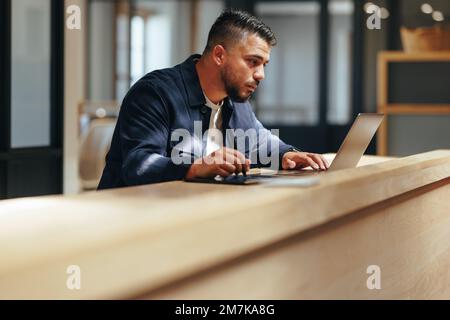Web design professionale che lavora su un computer portatile in un ufficio di coworking. Uomo d'affari creativo che disegnano su un tablet grafico. Designer maschile che fa lavoro a distanza Foto Stock