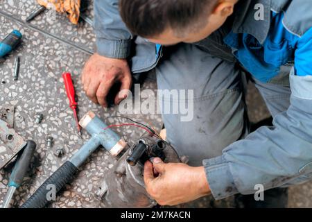 Riparazione meccanica del veicolo. Riparazione e diagnostica professionale di trattori e attrezzature cargo. Il meccanico in officina prende in considerazione i pezzi di ricambio. Vista dall'alto. Foto Stock