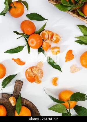 Composizione di tangerini e foglie mature fresche su fondo bianco, giacitura piatta. Vista dall'alto sugli agrumi Foto Stock