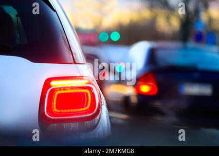 Luci posteriori per auto sulla strada cittadina la sera al tramonto in inverno, bassa velocità dell'otturatore. Foto Stock