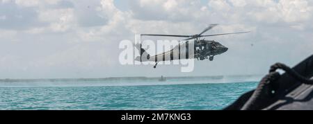 NEGLI STATI UNITI Esercito Sikorsky UH-60 Black Hawk elicottero trasporta Marines colombiani su una laguna per praticare salti di Helocast durante l'esercizio Tradewinds 2022 (TW22), a Bacalar Lagoon, Messico, 10 maggio 2022. TW22 è un ente statunitense Esercitazione multidimensionale, sponsorizzata dal comando meridionale dei Caraibi, condotta nei settori terrestre, aereo, marittimo e informatico, progettata per fornire alle nazioni partecipanti opportunità di condurre una formazione congiunta, combinata e interaziendale incentrata sull'aumento della cooperazione regionale e dell'interoperabilità in complesse operazioni di sicurezza multinazionali. Foto Stock