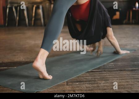 Donna irriconoscibile yoga e nuovo insegnante che fa un tre gambe rivolto verso il basso cane posa, allenamento yoga, a piedi nudi e indossare abbigliamento sportivo Foto Stock