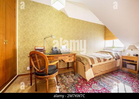 Camera con letto singolo, armadio a muro e scrivania in legno d''epoca in una camera mansardata Foto Stock