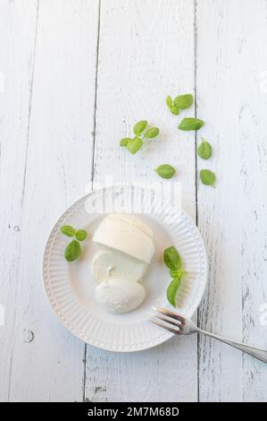 Mozzarella con foglie di basilico su un piatto isolato su sfondo bianco con spazio per il testo. Foto Stock