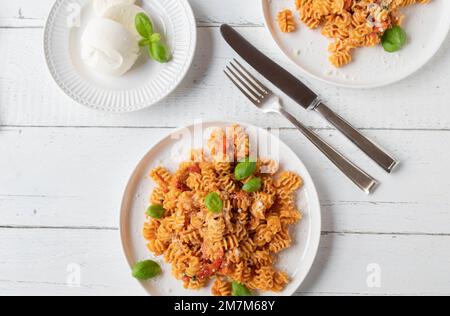 Pasta con pomodoro e mozzarella su un piatto. Giacitura piatta Foto Stock