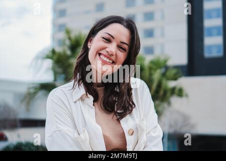 Ritratto di giovane donna sorridente e guardando la macchina fotografica con dente bianco in piedi all'aperto. Vista frontale di una ragazza adolescente felice con atteggiamento positivo. Foto di alta qualità Foto Stock