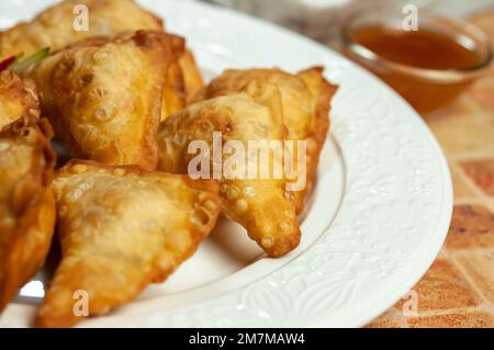 Wonton cinesi con salsa dolce al peperoncino e bastoncini tritare. Gnocchi fritti asiatici con salsa di soia su piatto bianco. Foto Stock