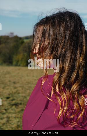 Profilo di una giovane donna incorniciata dai suoi capelli marrone chiaro Foto Stock