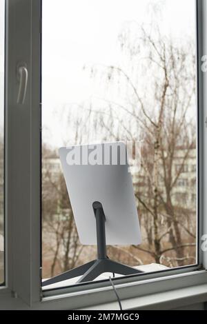 KIEV, UCRAINA - 8 GENNAIO 2023: Antenna Starlink per la ricezione del segnale nella finestra di un edificio alto. Foto Stock