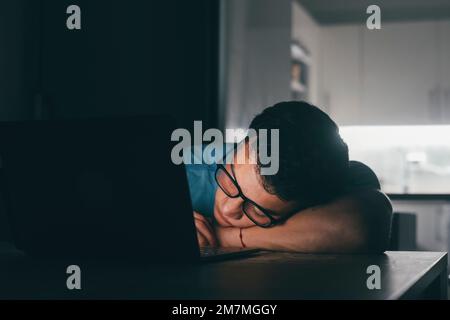 Primo piano uomo d'affari ha messo la testa sulle mani ripiegate che dormono sul posto di lavoro di notte. Sovraccarico di lavoro dipendente stanco di routine monotonia lavoro. Concetto di lavoratore non motivato, insonnia e sindrome da affaticamento cronico Foto Stock