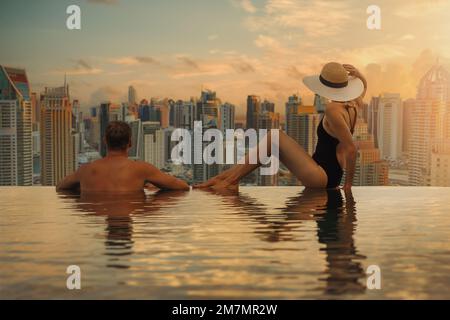 Coppia godendo lo skyline di Dubai con l'architettura dei grattacieli dalla piscina infinity dell'hotel al tramonto. vacanze di lusso e viaggi. Emirati Arabi Uniti Foto Stock