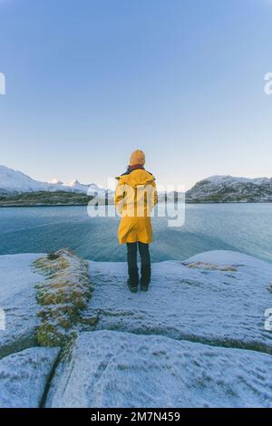 Giovane donna con impermeabile giallo in Norvegia, Lofoten, villaggio di pescatori Foto Stock