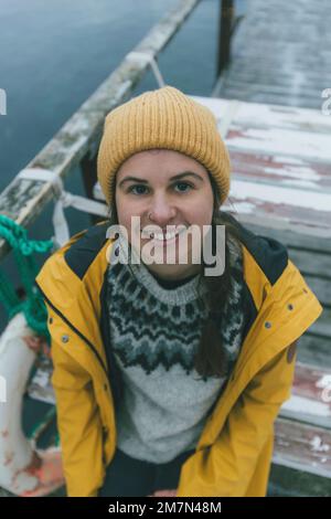 Giovane donna con impermeabile giallo in Norvegia, Lofoten, villaggio di pescatori Foto Stock