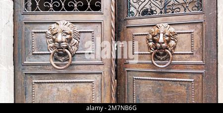 Porta frontale a doppia foglia con cornice in metallo e teste di leone come battitori nel villaggio di Cefalù, in Sicilia Foto Stock