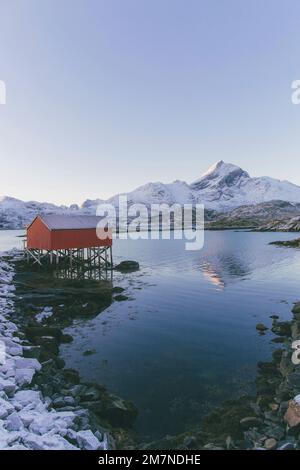 Tradizionale capanna di pesca su palafitte, Norvegia, tipico paesaggio fiordo con montagne e palafitte casa Foto Stock