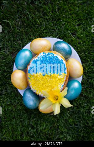 Torta di Pasqua decorata in colori di bandiera Ucraina e uova dipinte in giallo blu, disposti intorno ad essa. concetto di pasqua, tradizioni ucraine. Supporto U Foto Stock