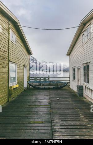 Vecchia casa di pescatori con barca e vecchio molo di legno in Norvegia, villaggio di pescatori inö ˆndalsnes, Norden. Foto Stock